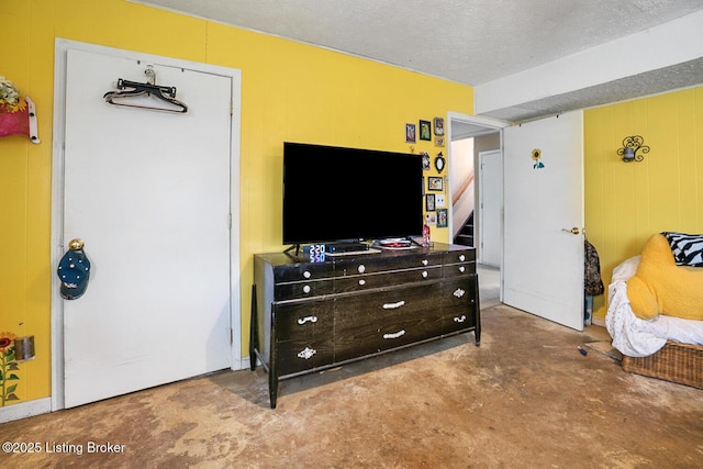 bedroom with wooden walls, concrete floors, and a textured ceiling