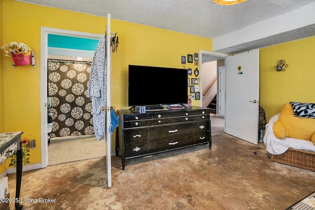 bedroom with a textured ceiling, wood walls, and concrete flooring