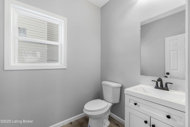 bathroom with toilet, vanity, and wood-type flooring