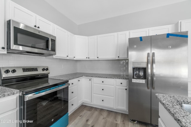 kitchen with appliances with stainless steel finishes, white cabinets, tasteful backsplash, and light stone countertops