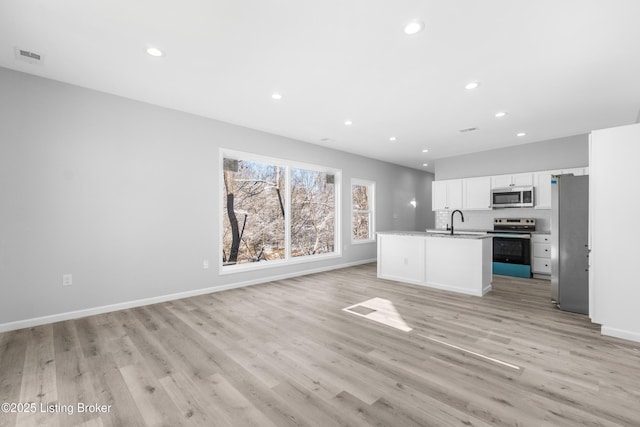 kitchen featuring a center island with sink, light hardwood / wood-style flooring, stainless steel appliances, and white cabinetry