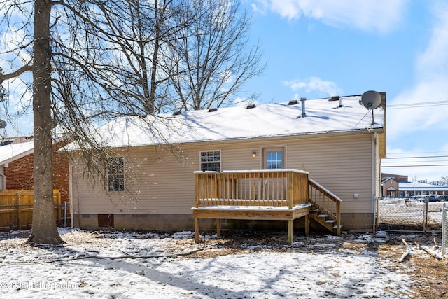 snow covered back of property with a deck