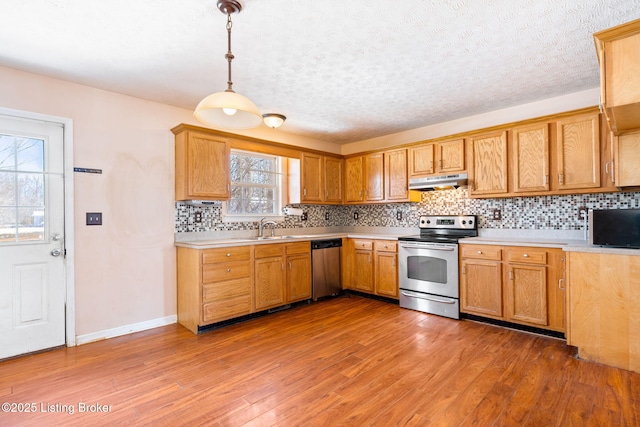 kitchen with hardwood / wood-style floors, decorative backsplash, appliances with stainless steel finishes, and decorative light fixtures