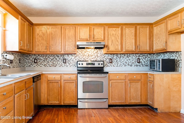 kitchen featuring stainless steel appliances, a textured ceiling, backsplash, sink, and dark hardwood / wood-style floors