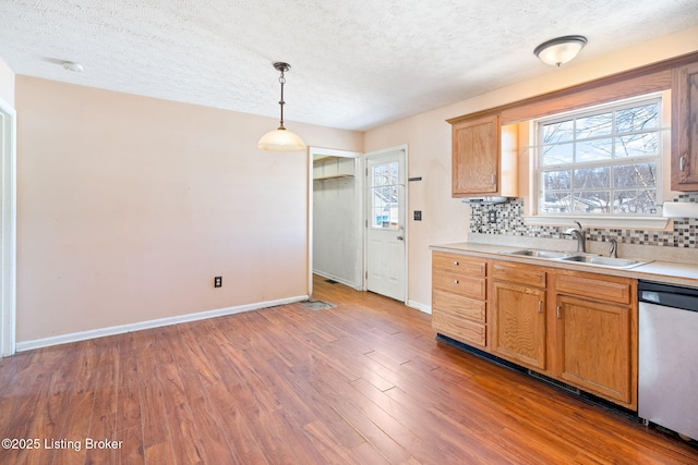 kitchen with hardwood / wood-style flooring, sink, tasteful backsplash, dishwasher, and pendant lighting