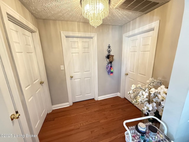 interior space with baseboards, a textured ceiling, visible vents, and wood finished floors