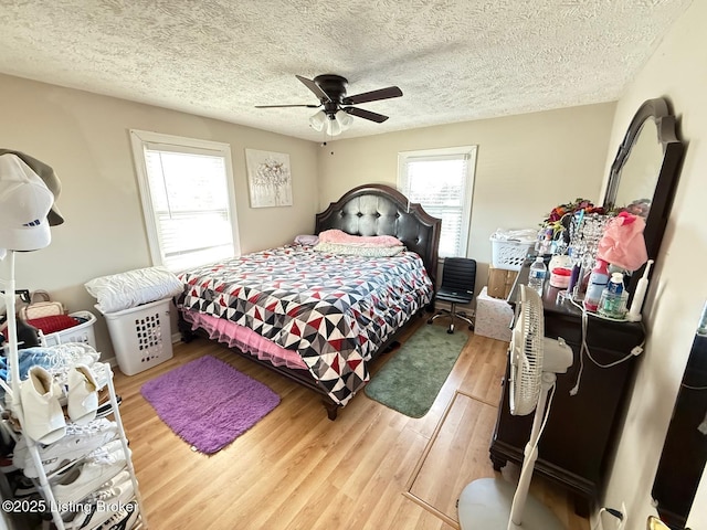 bedroom with a textured ceiling, a ceiling fan, and wood finished floors