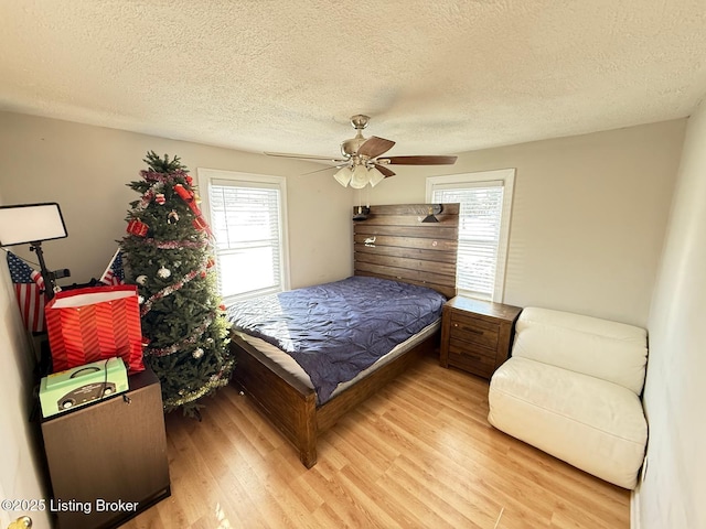 bedroom with a textured ceiling, ceiling fan, and wood finished floors