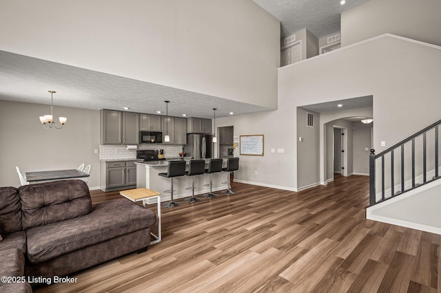 living area with visible vents, baseboards, arched walkways, wood finished floors, and stairs