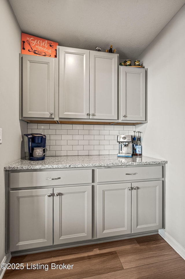kitchen with dark wood finished floors, backsplash, and light stone countertops