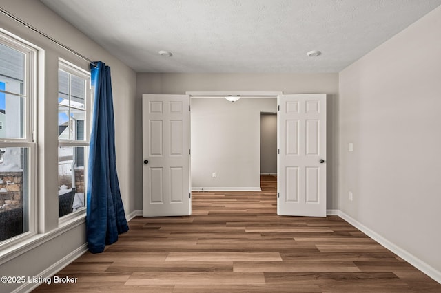 unfurnished bedroom with baseboards, a textured ceiling, and wood finished floors