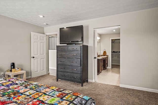 bedroom featuring light carpet, a textured ceiling, and baseboards