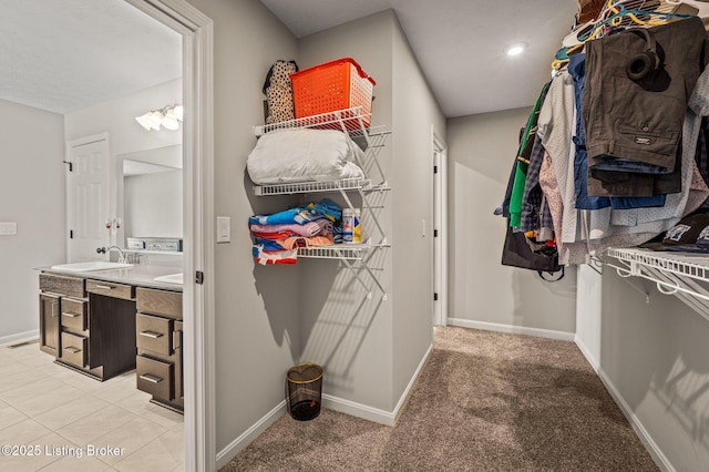 walk in closet with light carpet, light tile patterned floors, and a sink