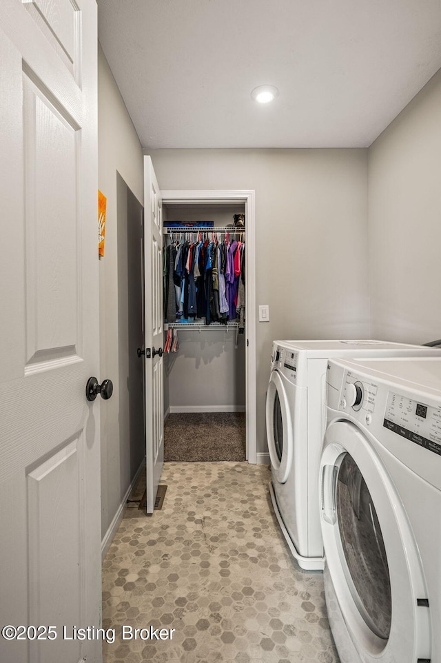 washroom with baseboards, washer and dryer, and laundry area
