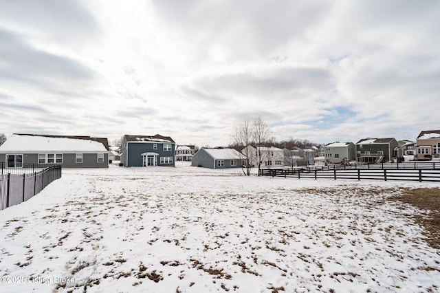 yard layered in snow with fence and a residential view