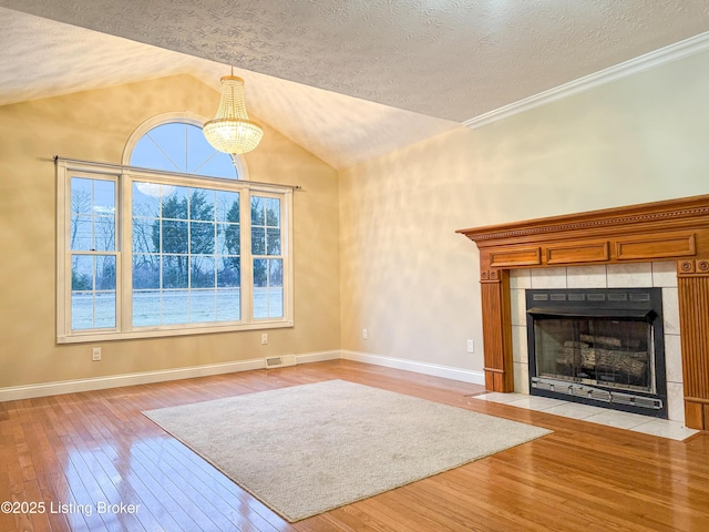 unfurnished living room featuring light hardwood / wood-style flooring, a tiled fireplace, a textured ceiling, and lofted ceiling