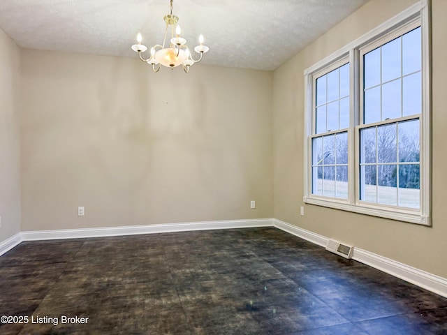 spare room with a chandelier and a textured ceiling