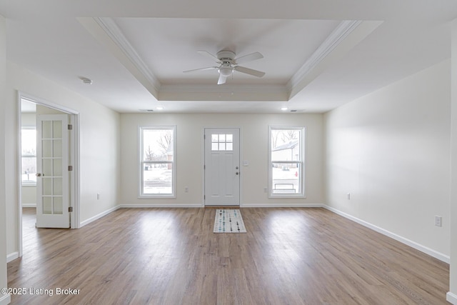 foyer with ceiling fan, a raised ceiling, crown molding, and light hardwood / wood-style floors