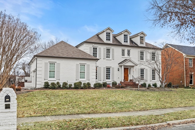 view of front of house with brick siding, a front lawn, and a shingled roof