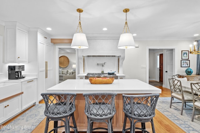 kitchen featuring hanging light fixtures, white cabinets, light countertops, and a center island