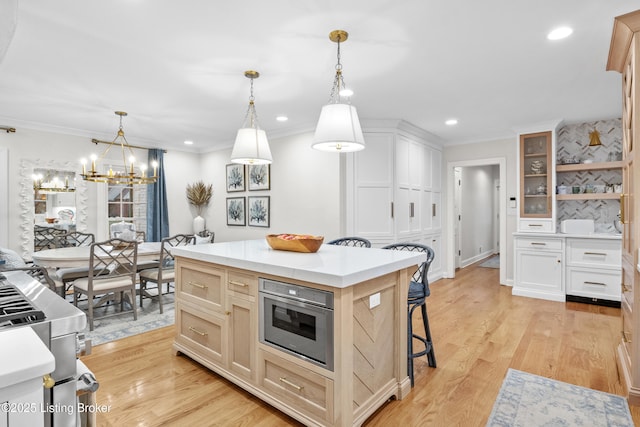 kitchen with a kitchen island, glass insert cabinets, a kitchen breakfast bar, hanging light fixtures, and light countertops