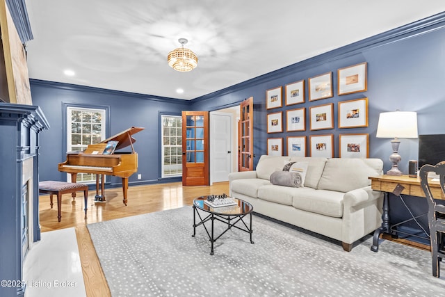 living area with baseboards, a fireplace, wood finished floors, and crown molding