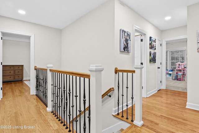 corridor with light wood-style floors, recessed lighting, baseboards, and an upstairs landing