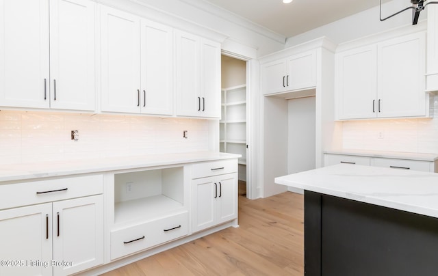 kitchen featuring white cabinetry, light wood-type flooring, and light stone counters