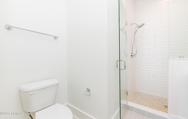 bathroom featuring toilet and a shower with shower door