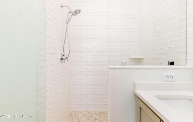 bathroom featuring tiled shower and vanity