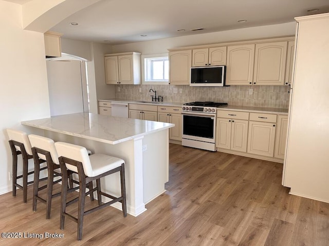 kitchen featuring a peninsula, white appliances, a sink, and a breakfast bar