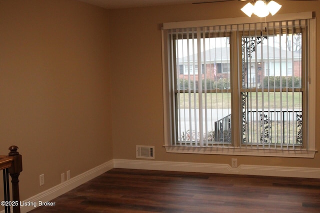 unfurnished room featuring dark wood-type flooring and a wealth of natural light