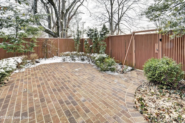 snow covered patio featuring a fenced backyard