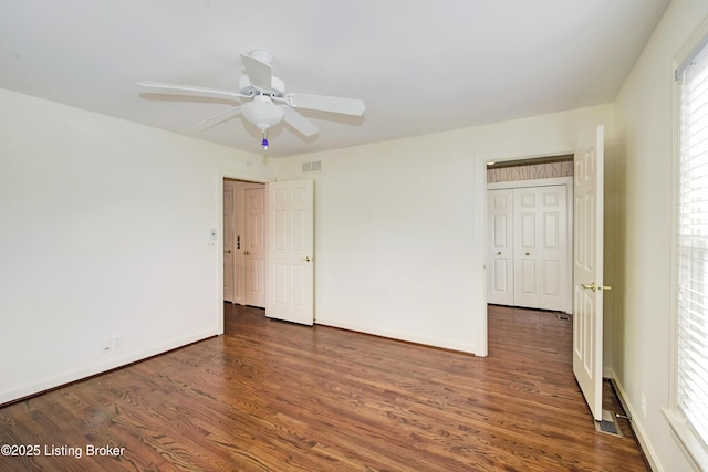 unfurnished bedroom featuring dark wood-style floors, ceiling fan, visible vents, and baseboards