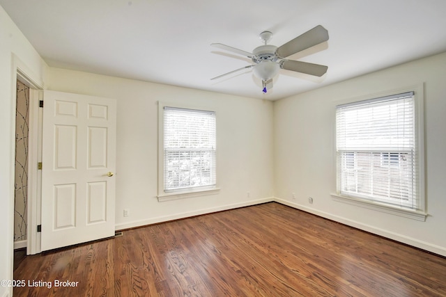 empty room featuring dark wood-style floors, baseboards, and a wealth of natural light