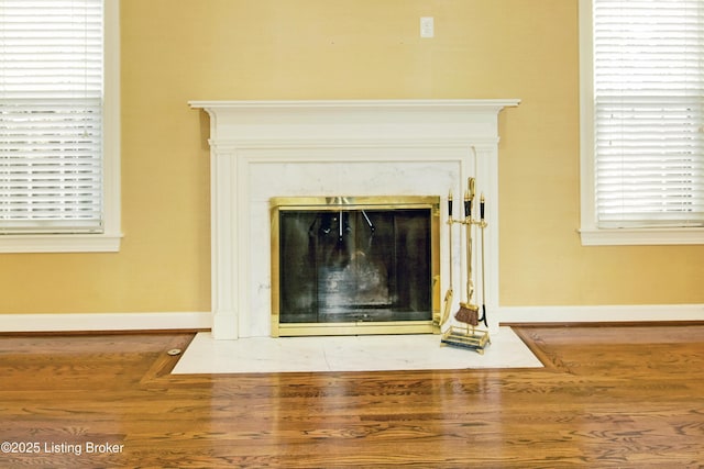 interior details with a high end fireplace, baseboards, and wood finished floors