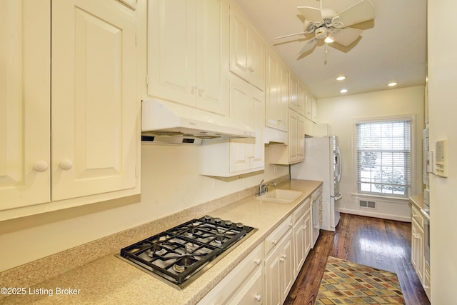 kitchen with under cabinet range hood, stainless steel gas cooktop, light countertops, and a sink