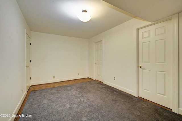 unfurnished room with dark carpet and baseboards