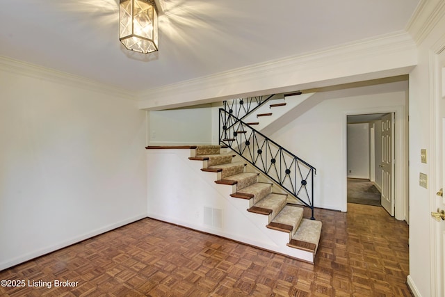 staircase with baseboards, visible vents, and crown molding