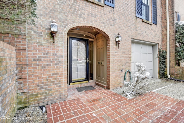 view of exterior entry featuring brick siding, driveway, and an attached garage