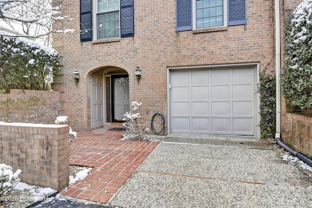 property entrance with an attached garage, driveway, and brick siding