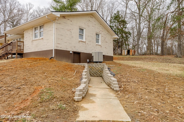 view of home's exterior with central AC unit and a storage unit