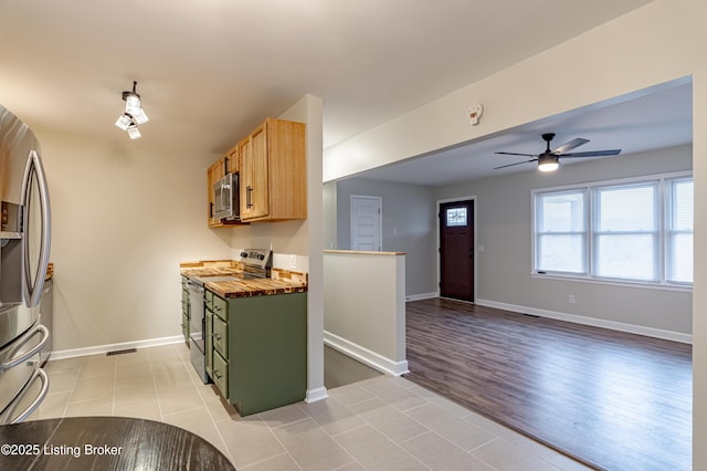 kitchen with green cabinetry, appliances with stainless steel finishes, ceiling fan, and light tile patterned floors