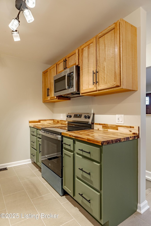 kitchen with green cabinets, wood counters, appliances with stainless steel finishes, light brown cabinets, and light tile patterned flooring