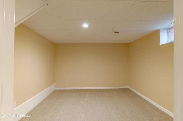 carpeted empty room featuring a drop ceiling