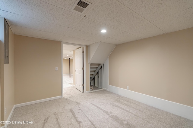 basement featuring a paneled ceiling and carpet flooring