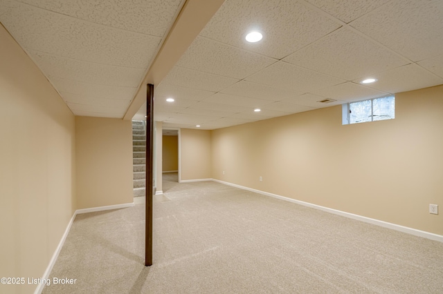 basement with a paneled ceiling and carpet floors