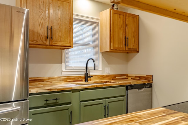 kitchen with appliances with stainless steel finishes, butcher block countertops, and sink