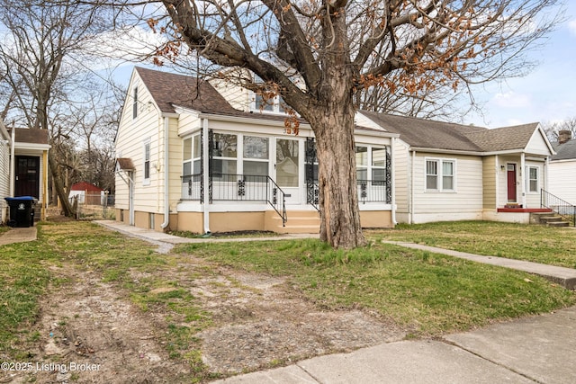 bungalow-style house featuring a shingled roof, a front yard, and fence