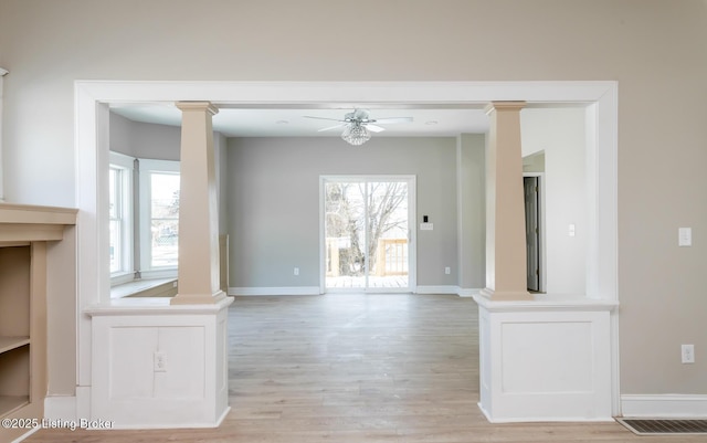 interior space featuring decorative columns, ceiling fan, and light hardwood / wood-style floors